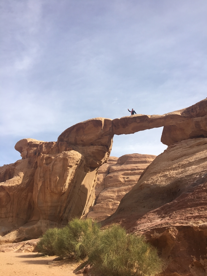 Personne debout sur un pont rocheux naturel dans un paysage désertique.
