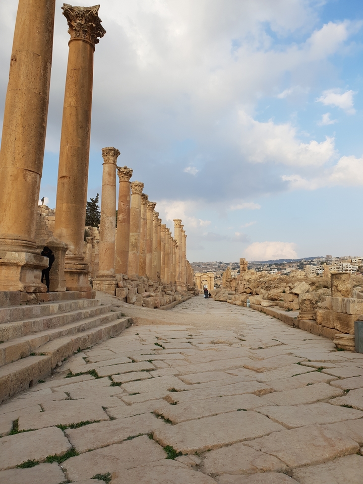 Ancient Roman ruins with a colonnade leading to an archway.