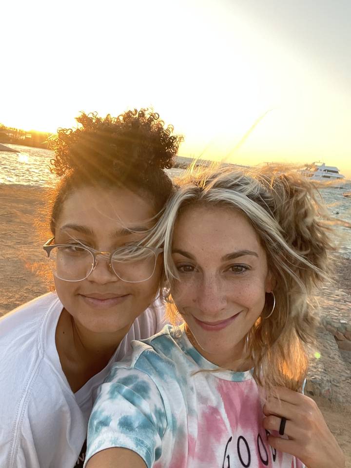 Two people taking a selfie with the sunset in the background.