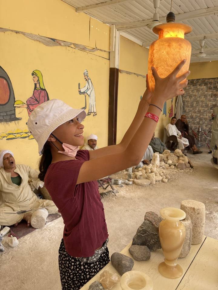 Child admiring a large glowing stone indoors.
