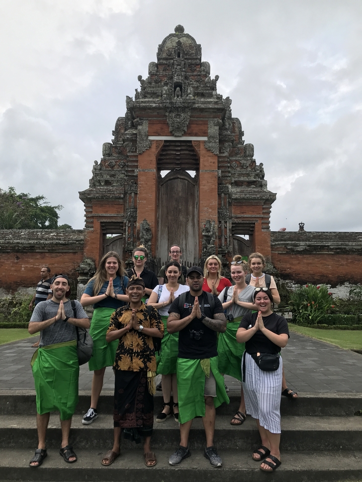 Group posing in front of a traditional red brick gateway.