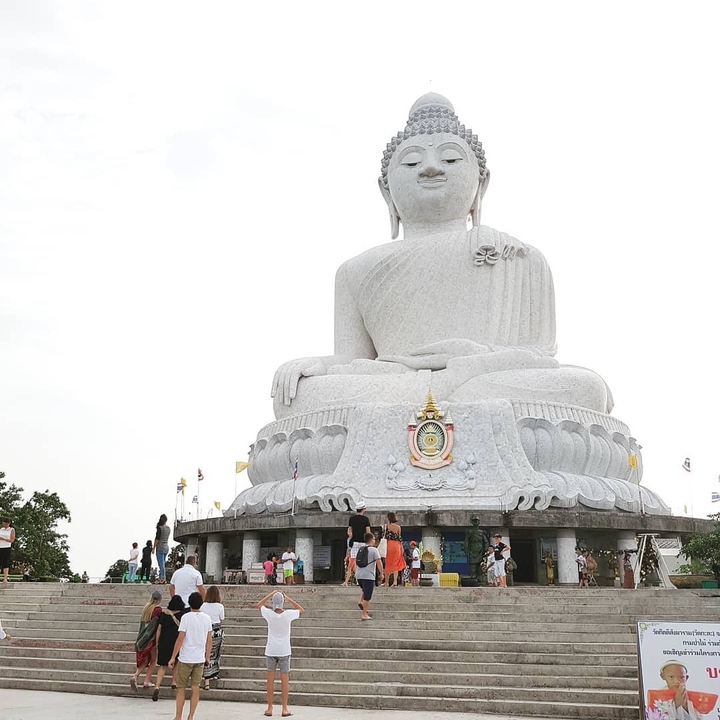 Large white Buddha statue with tourists around.