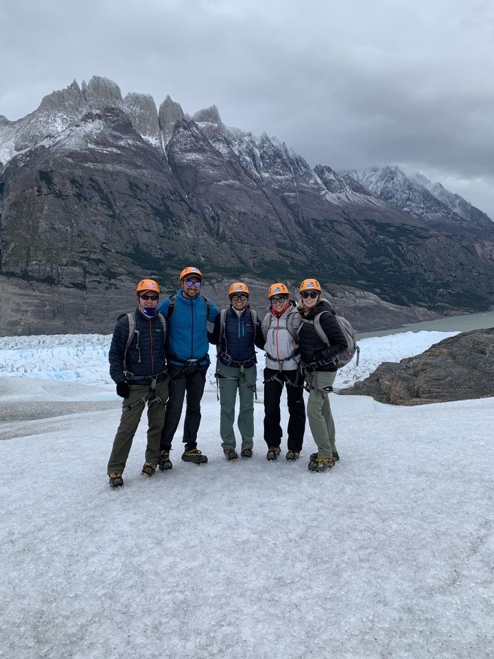 Group of people in cold weather gear posing on a glacier.