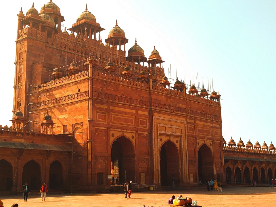 A large, red sandstone architectural structure with arches and domes.