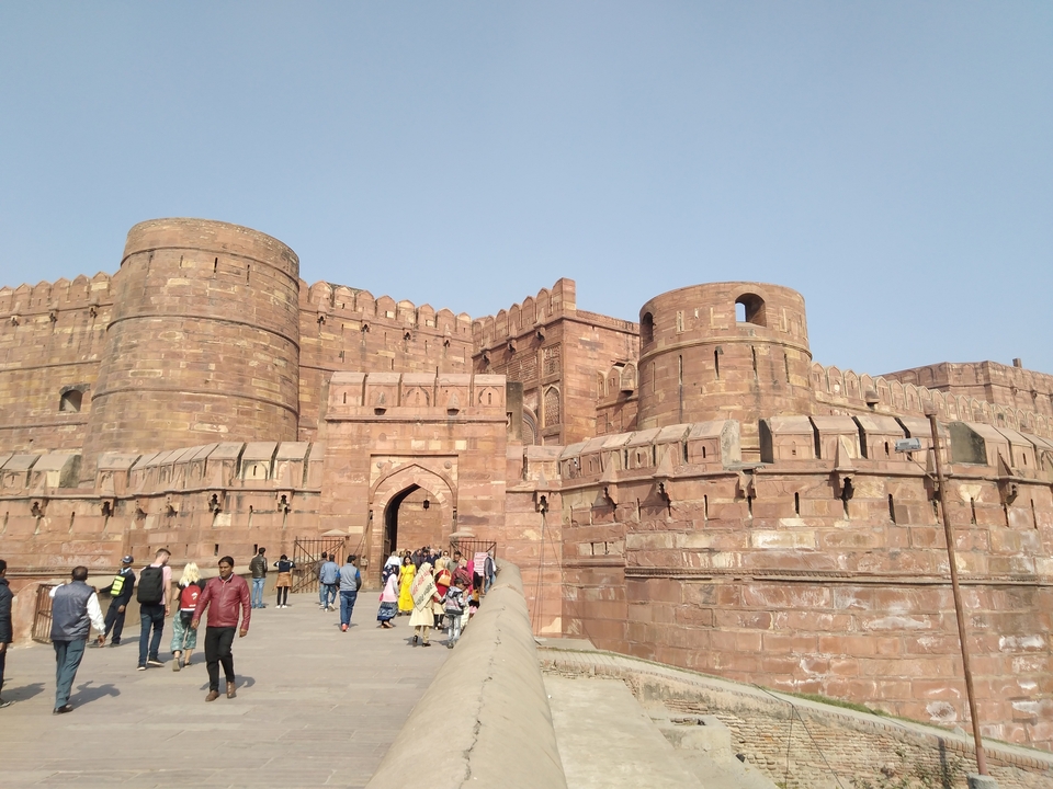 Large historic fort with tourists walking along the entrance.