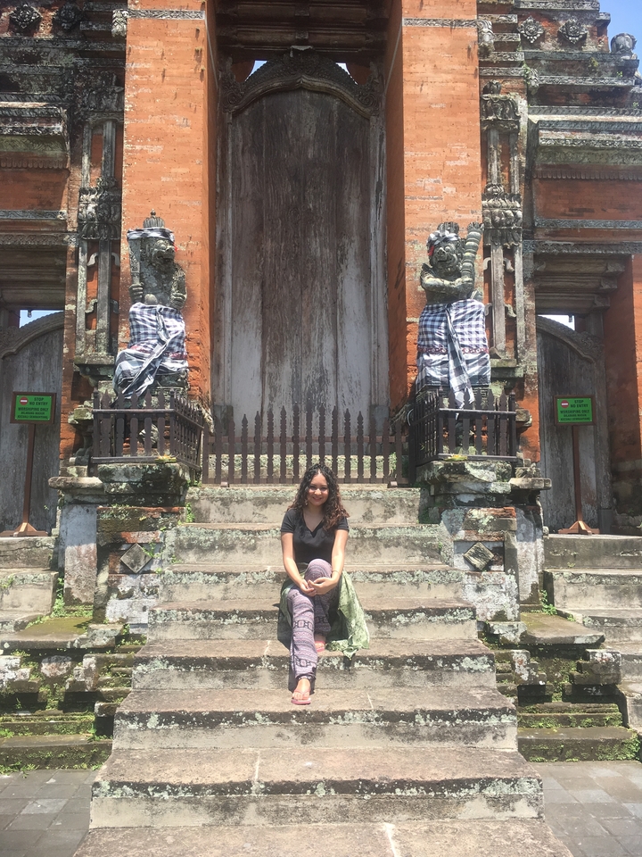 Person sitting in front of a traditional gateway with statues.
