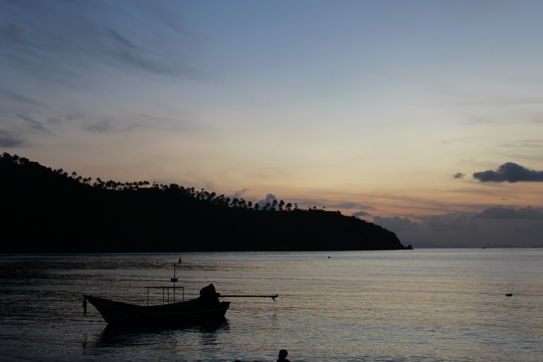 Silhouette of a boat at sunset on the water.
