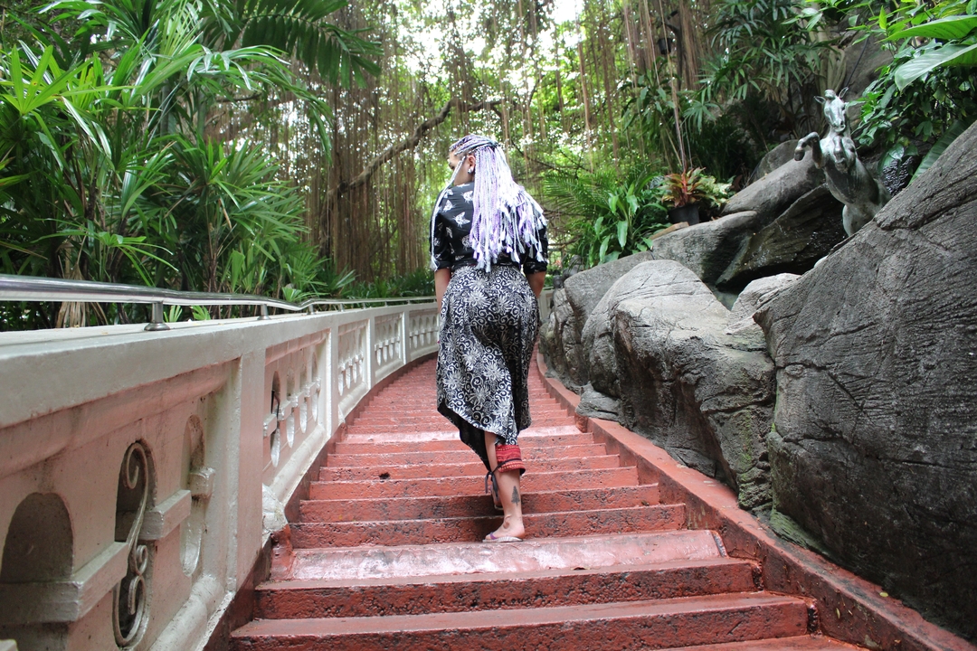 Person walking up steps in a lush garden.