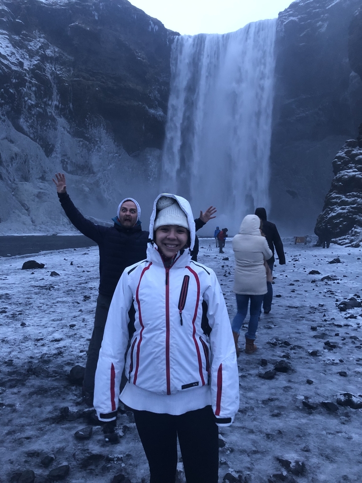 Group of tourists in front of a snowy waterfall.