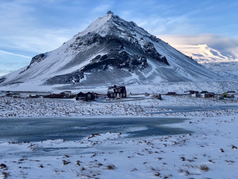 Snowy mountains with a lonely house in the foreground.