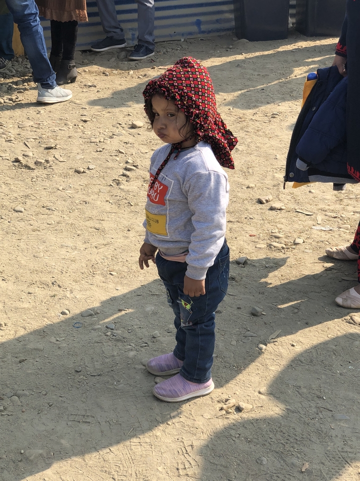 Jeune enfant debout sur une surface rocheuse portant des vêtements décontractés.