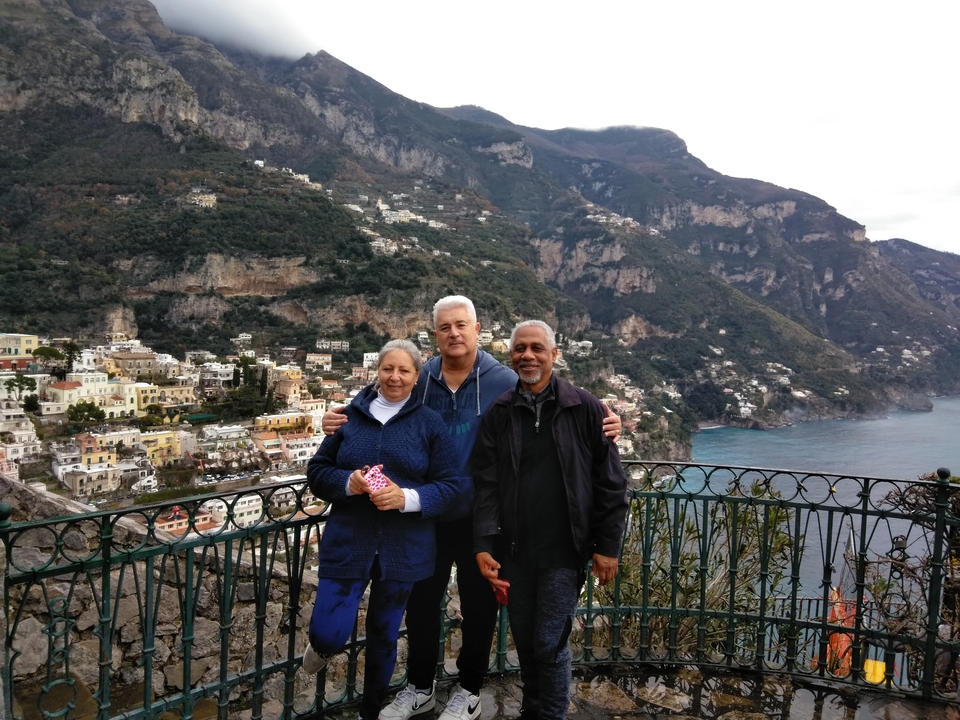 Three people posing with a scenic view of Positano.