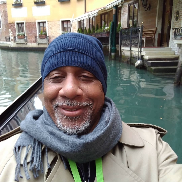 Selfie of a person in a canal setting with gondolas.