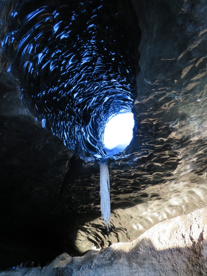 Interior view of a glacial ice cave with blue ice walls.