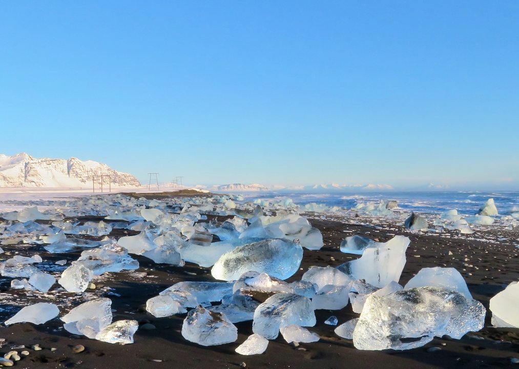 Diamond Beach with ice chunks on black sand, ocean in the background.