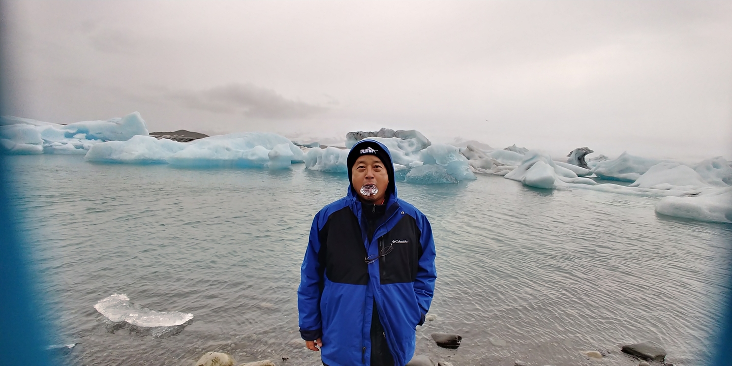 Homme debout près d'un plan d'eau avec des icebergs flottants.