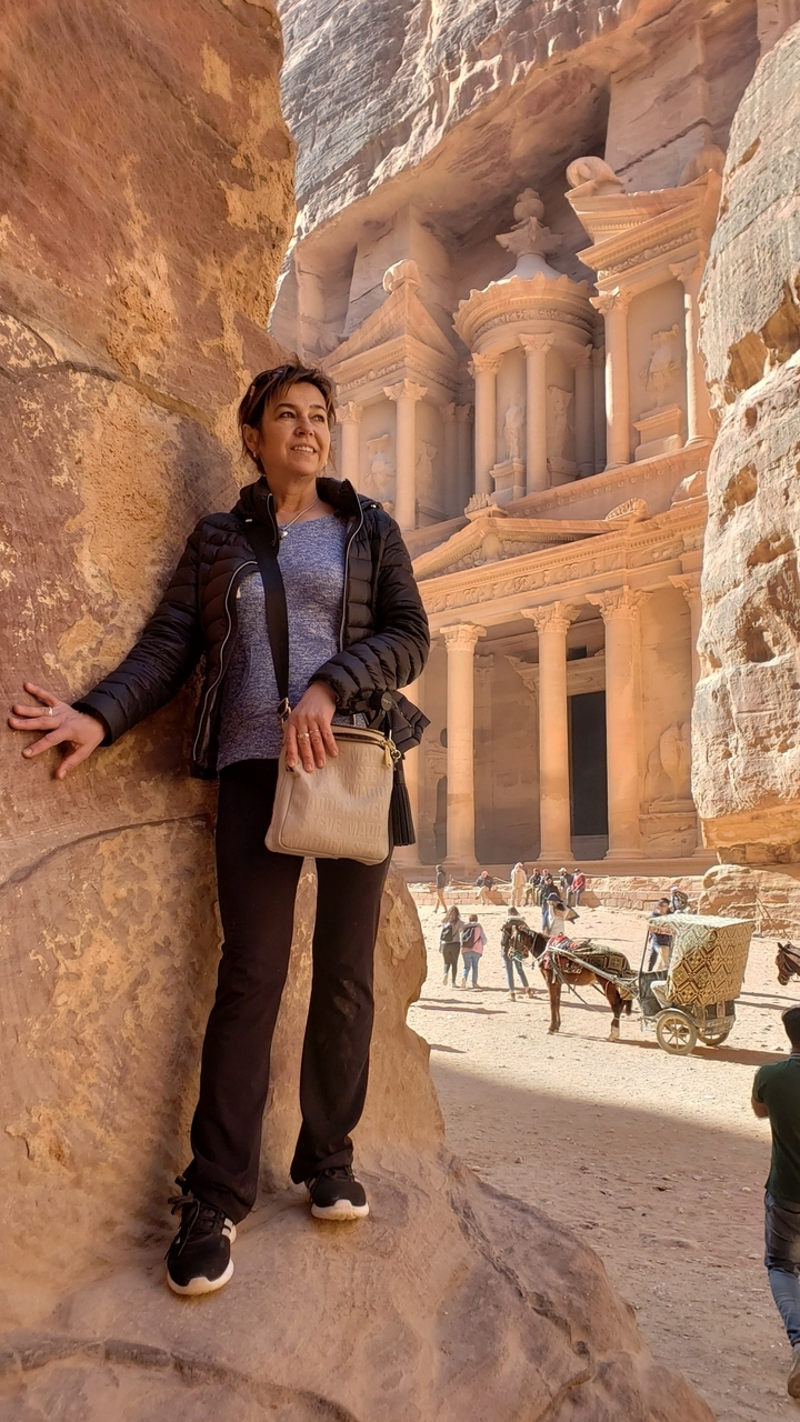 A person posing in front of the ancient Treasury in Petra.