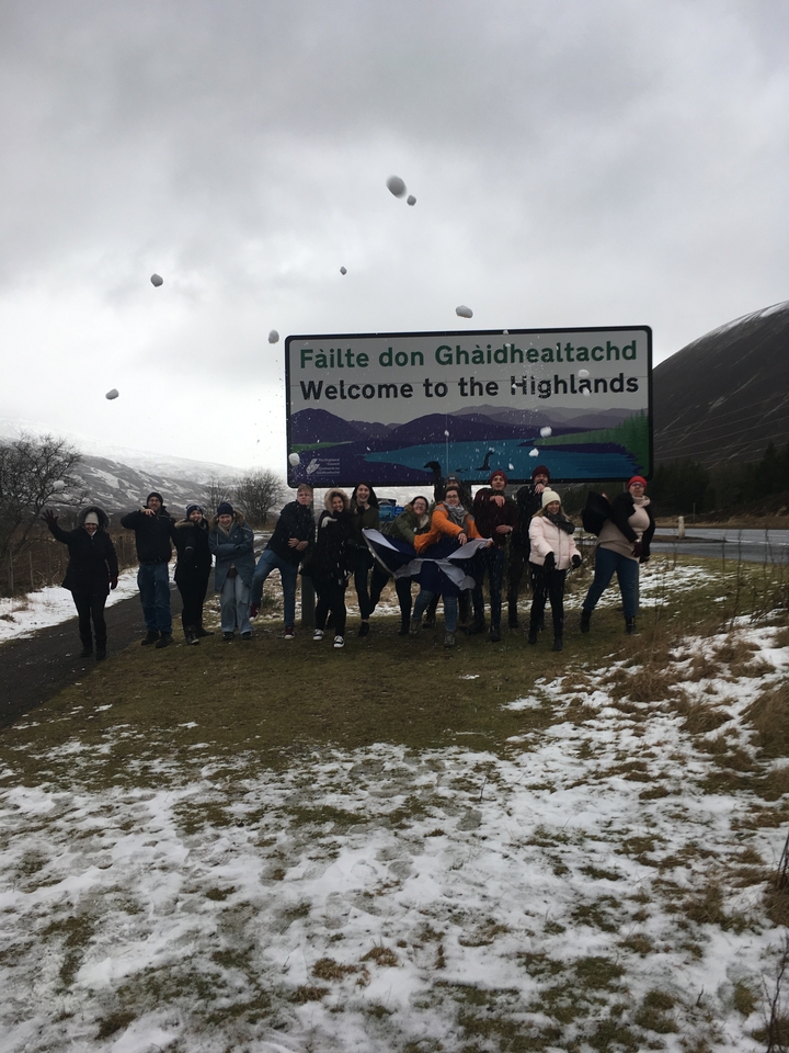 Group of people with snowballs by a Welcome to the Highlands sign.