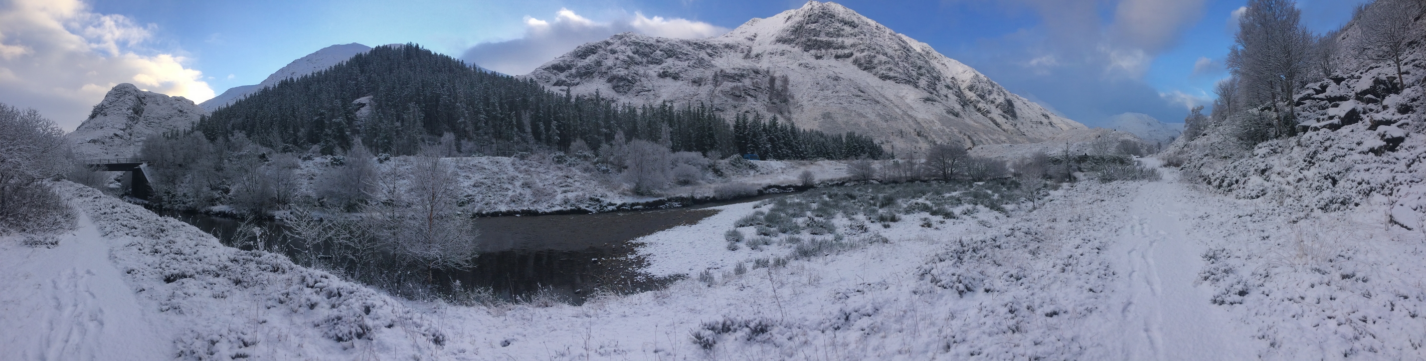 Snowy mountains with a river in the foreground.