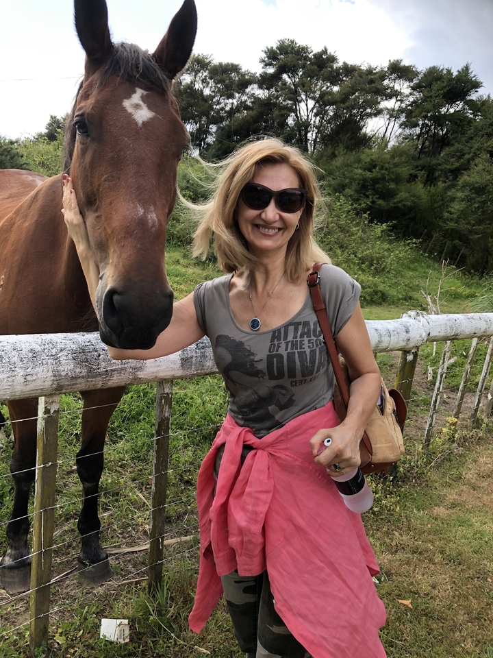 Person smiling while standing next to a horse.