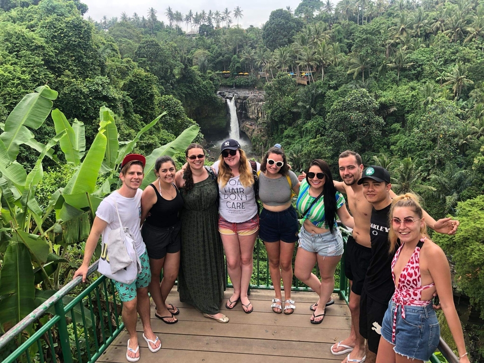 Group of people posing with a waterfall in the background.
