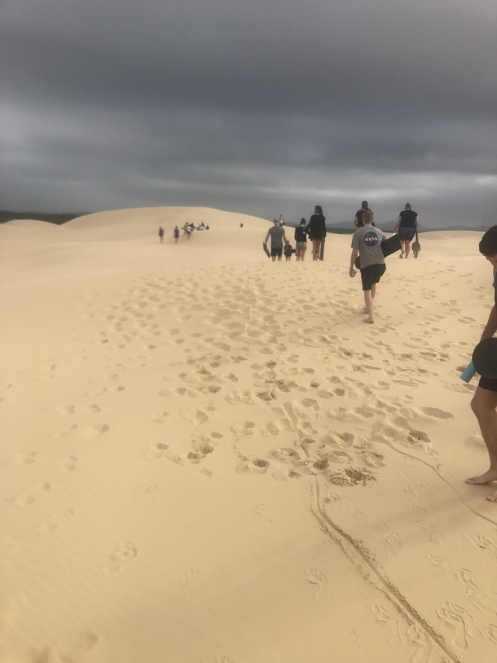 Group of people walking on sand dunes.