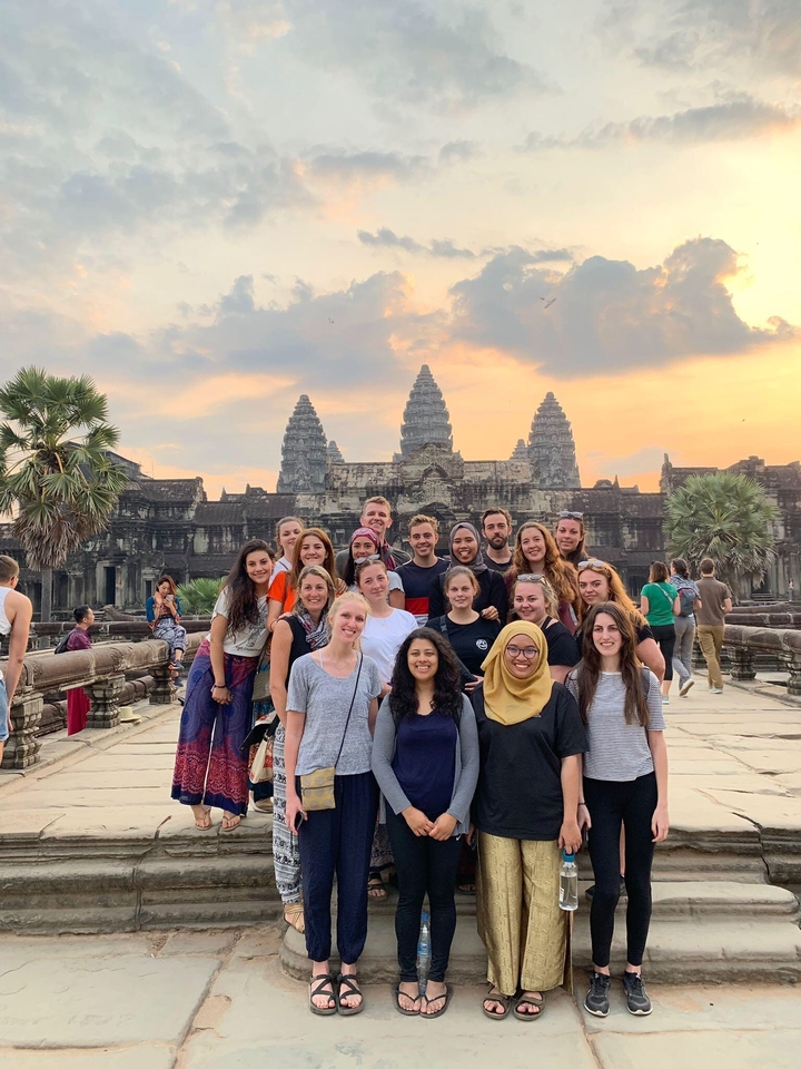 Group of people posing in front of Angkor Wat during sunset.