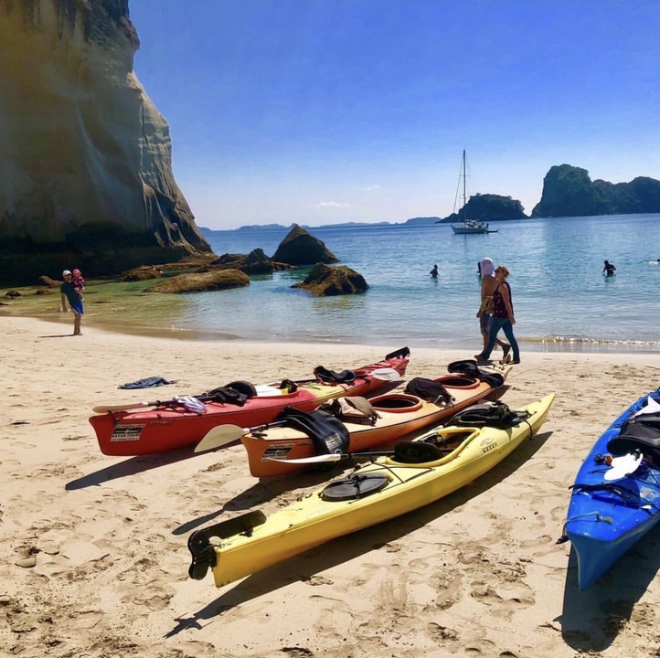 Kayaks on a sandy beach with calm waters.