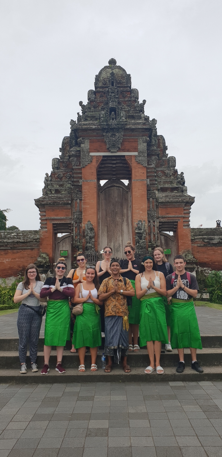 Group of people posing in front of an ornate gate.