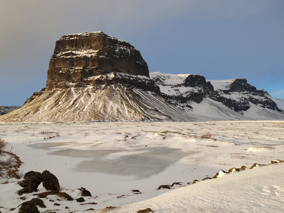 Montagne enneigée et paysage gelé sous un ciel bleu.