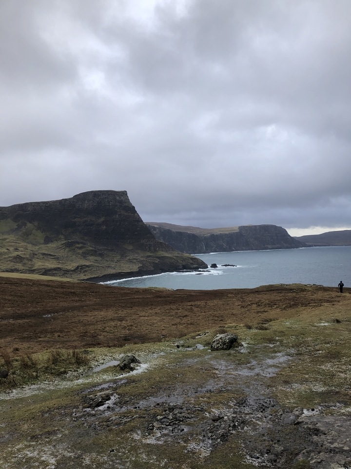 Cliffs and ocean with a lone figure.