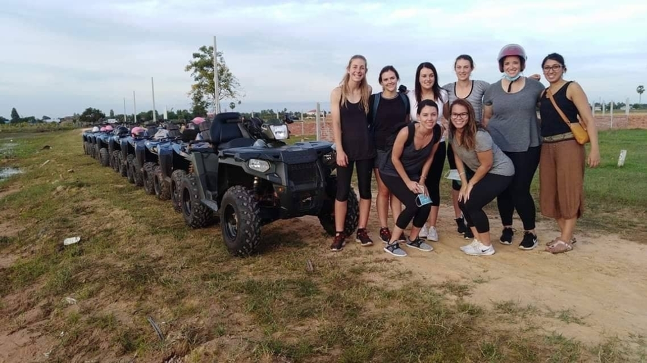 Group of people posing beside ATVs.