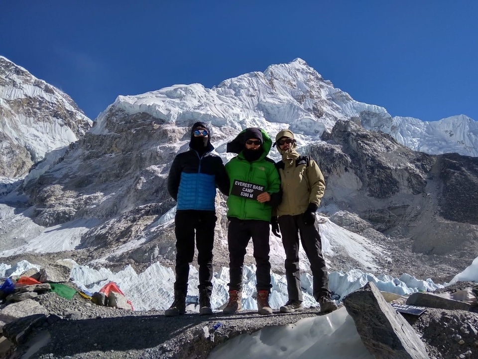 Trois personnes au camp de base de l'Everest avec vue sur la montagne.