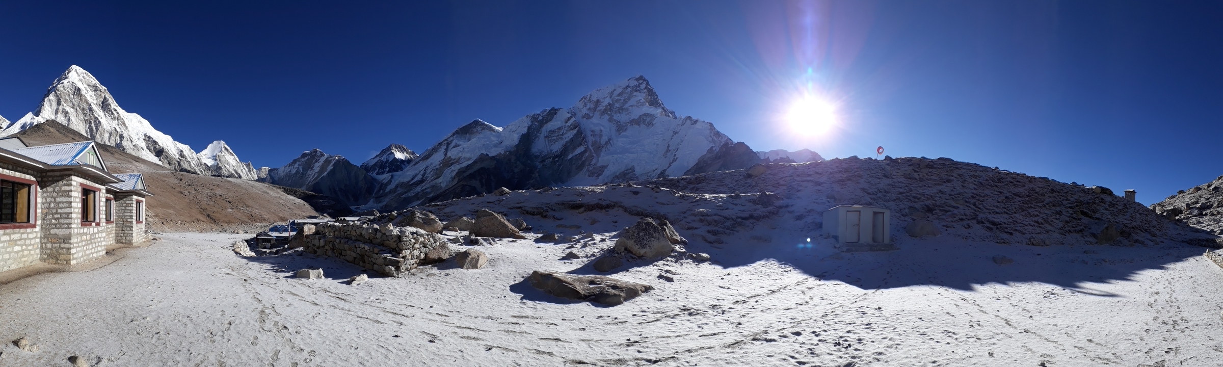 Montagnes enneigées sous un ciel bleu clair et un soleil éclatant.