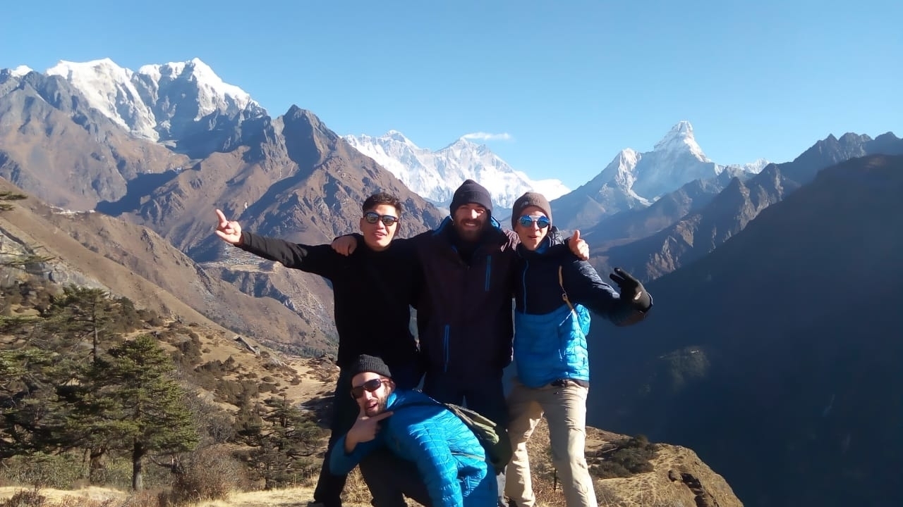 Groupe d'amis posant avec des montagnes en arrière-plan.