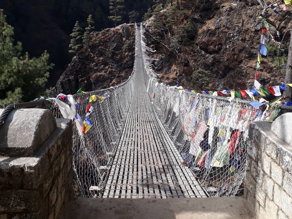 Pont suspendu décoré de drapeaux de prière.