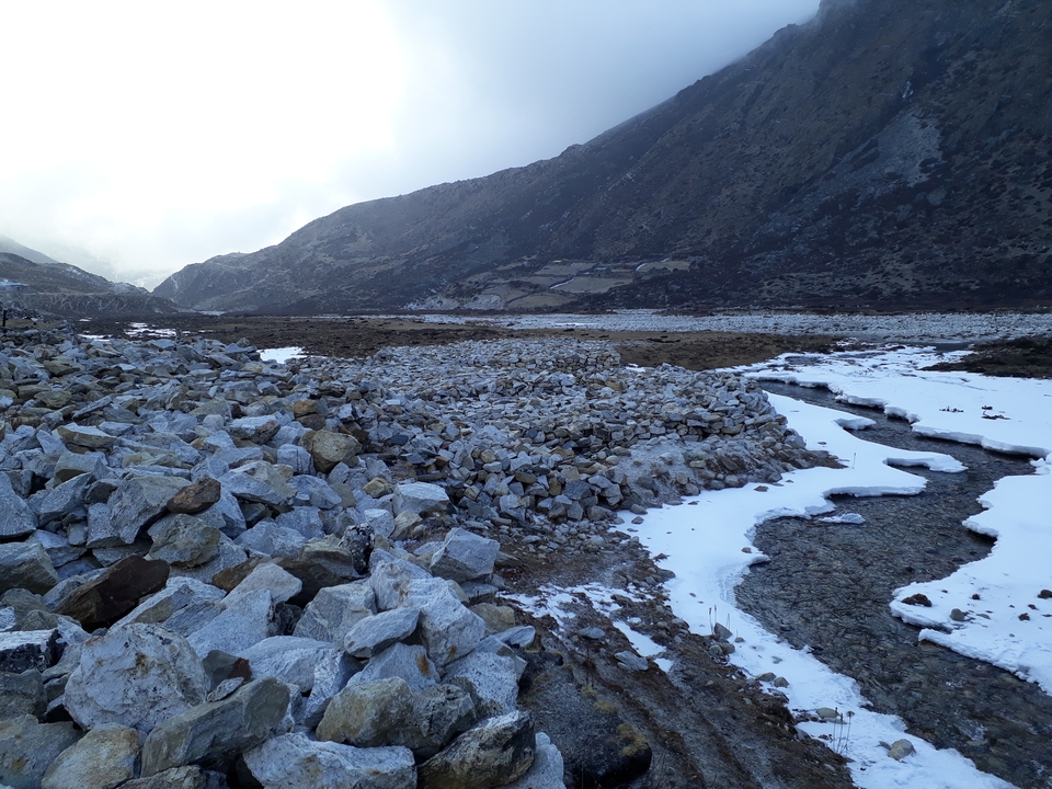 Lit rocheux de rivière avec un ruisseau et des montagnes.