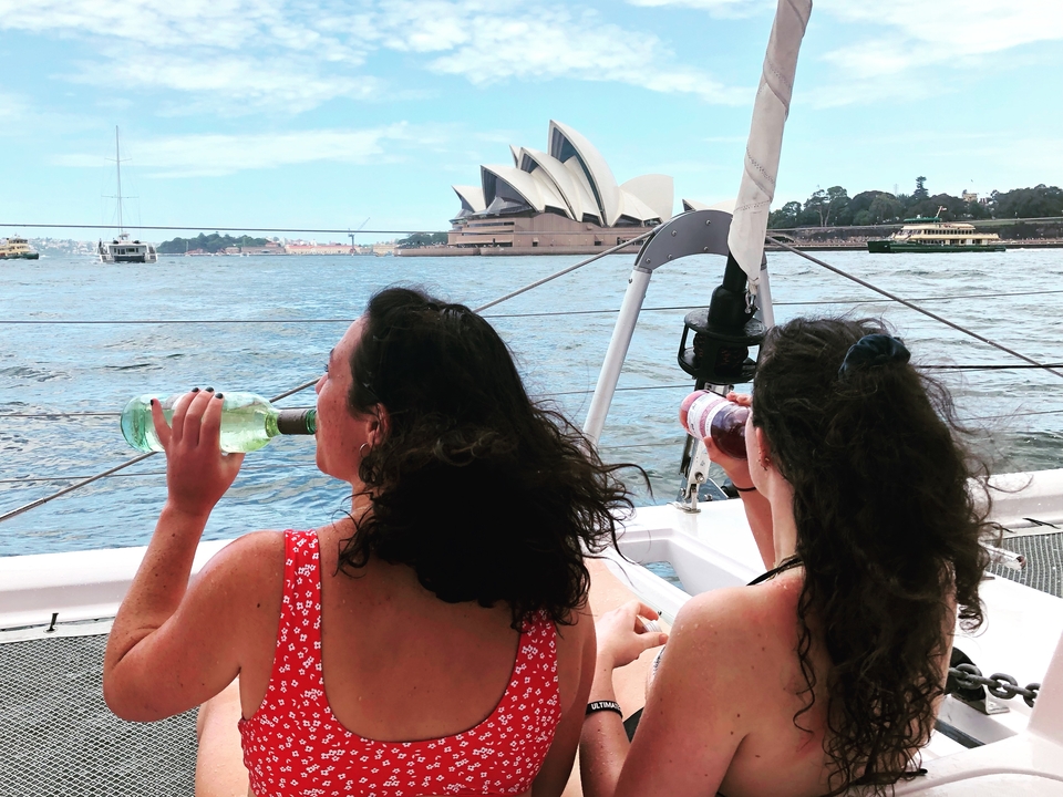 People enjoying a boat ride with the Sydney Opera House in the background.