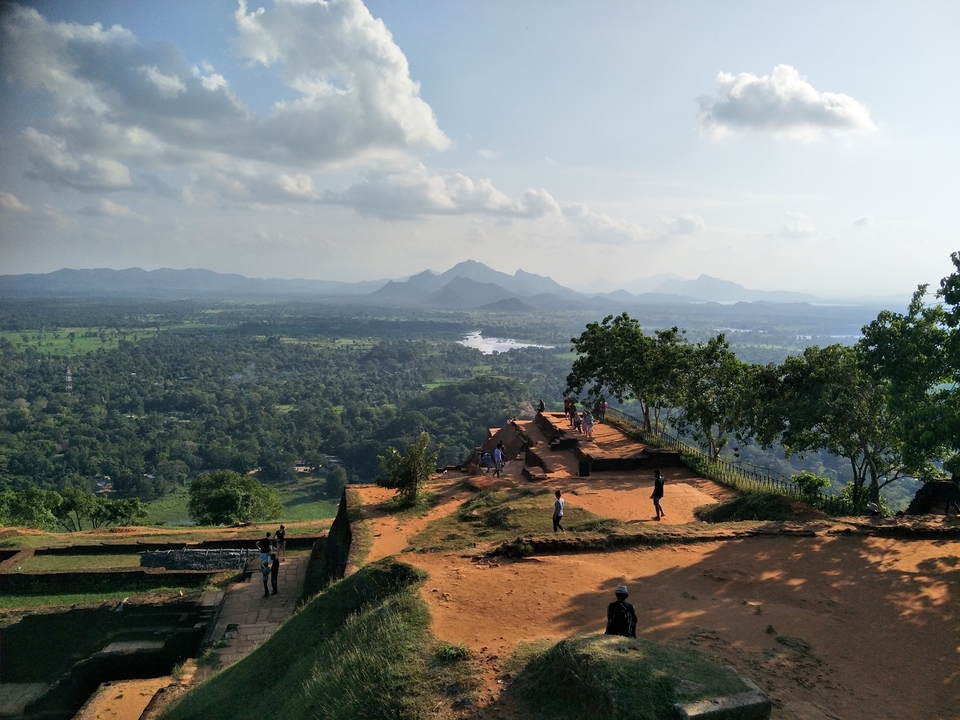 People walking on a hilltop with expansive views of a lush valley.
