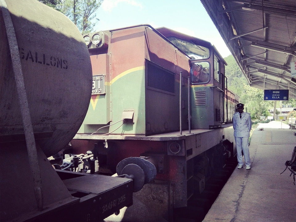 Train at a station with a person standing next to it.