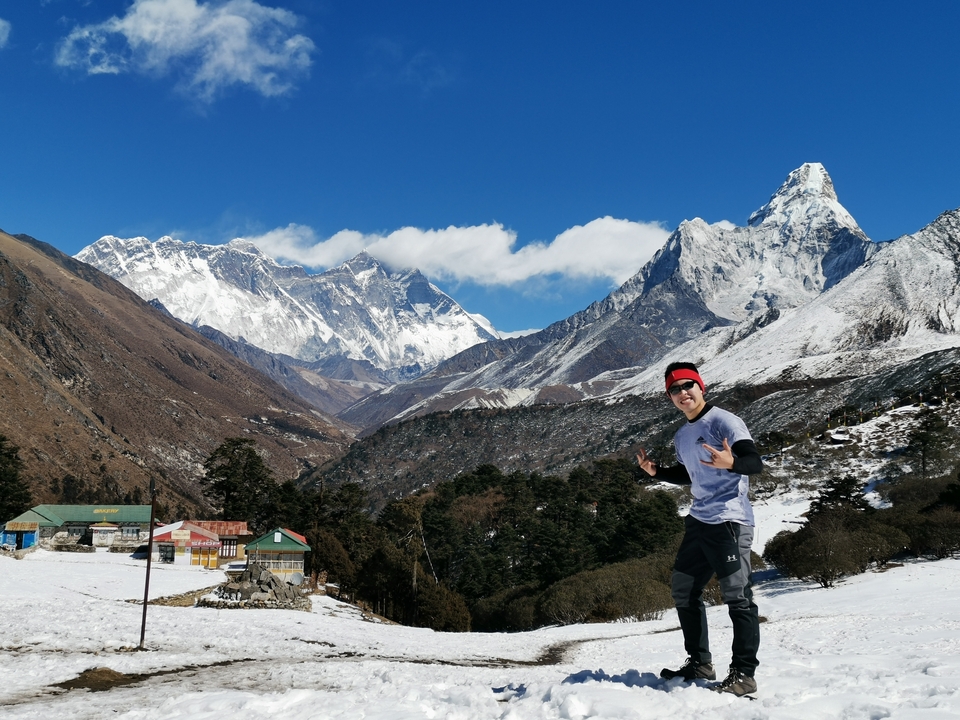 Homme posant dans un paysage himalayen enneigé.