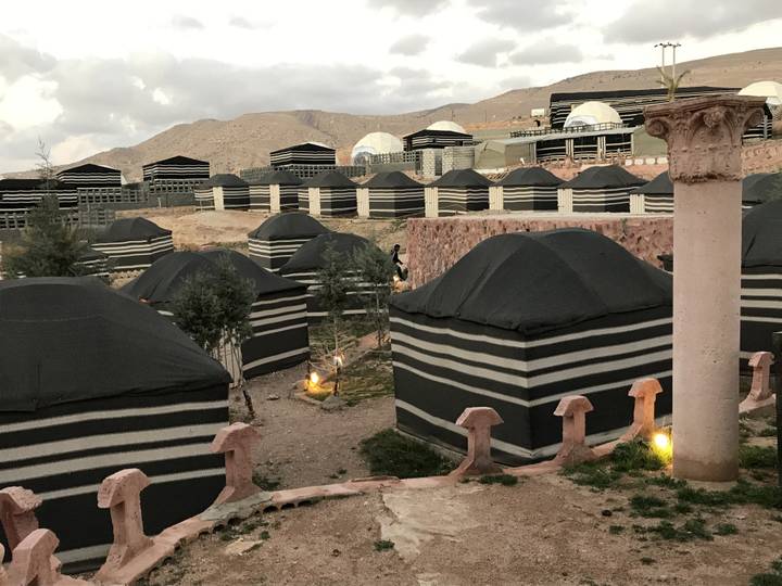 Row of tents resembling Bedouin style in a desert setting.