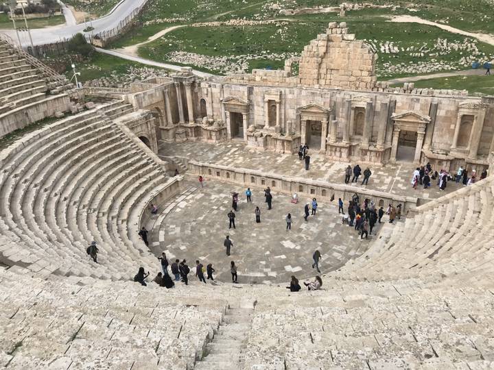 Ancient Roman amphitheater with people exploring.