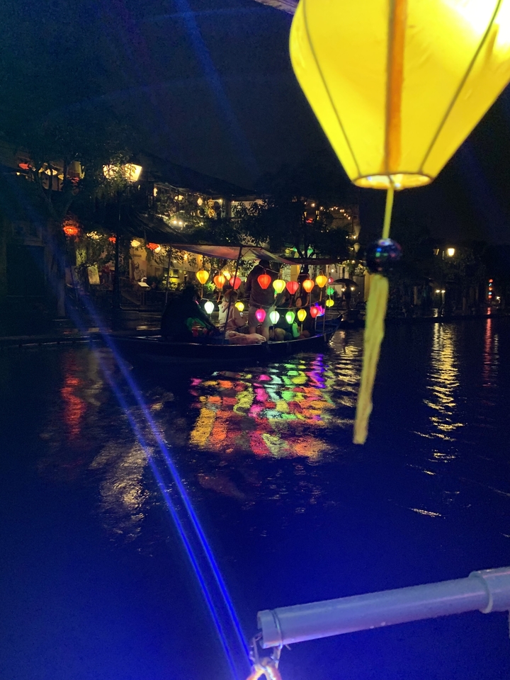 Boat on a river adorned with colorful lanterns at night.