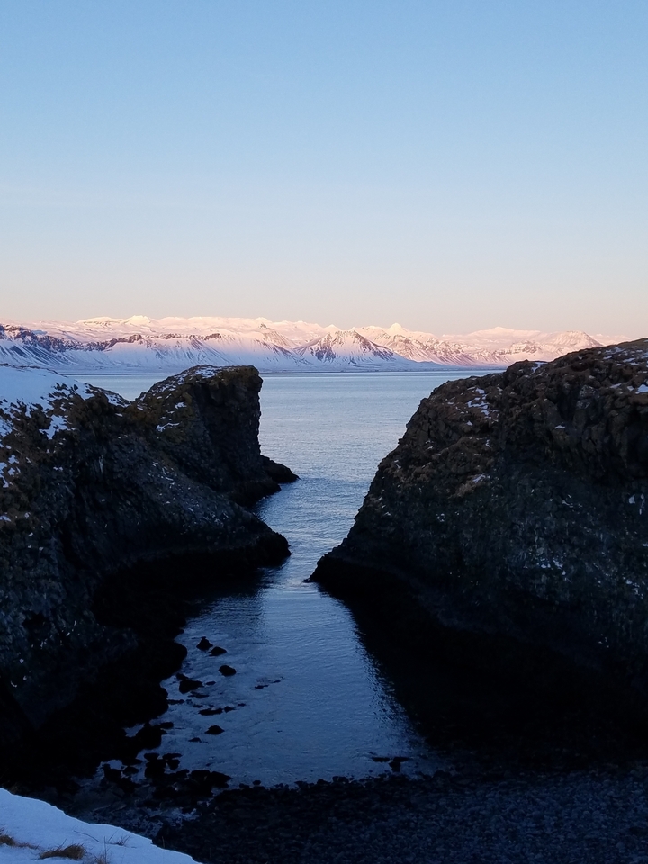 Snow-covered mountains with a body of water in the foreground.