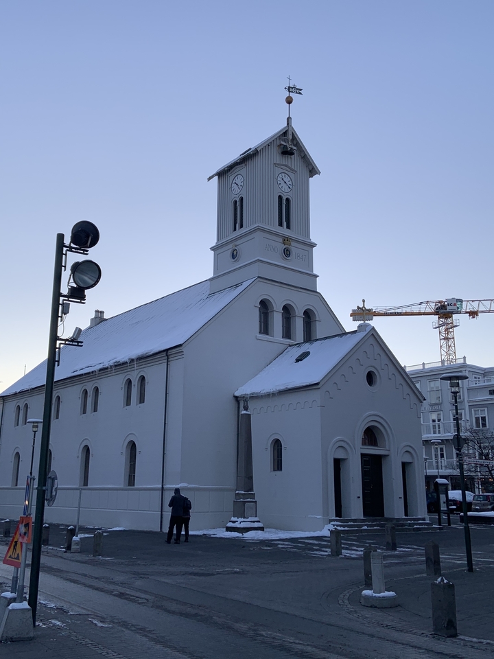 Snow-covered church with a crane in the background.
