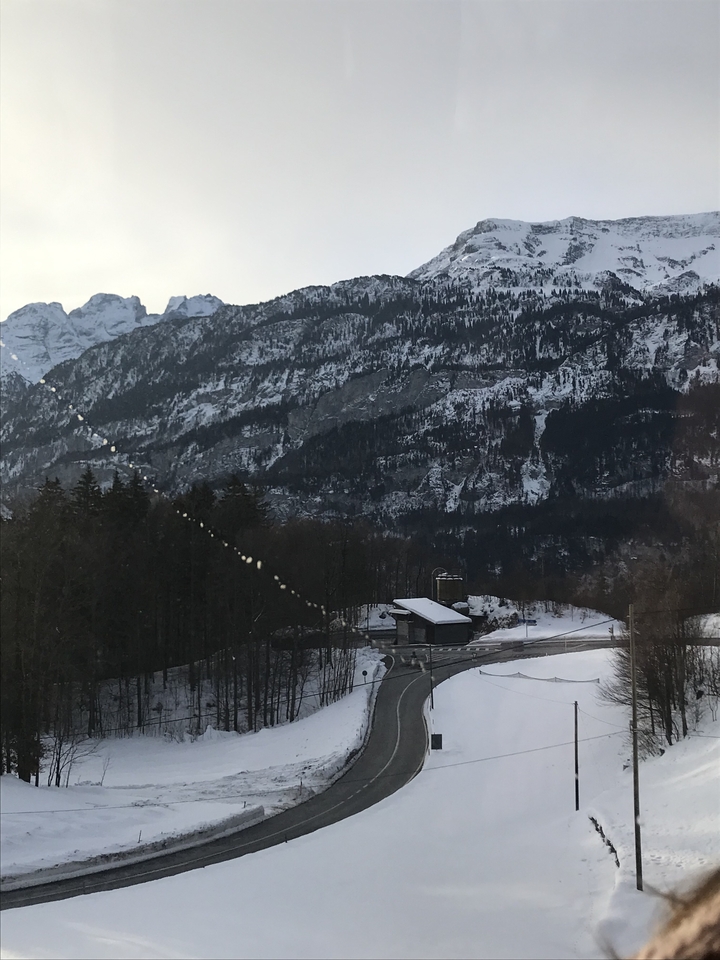 Mountain landscape with snow and a small building in the valley.