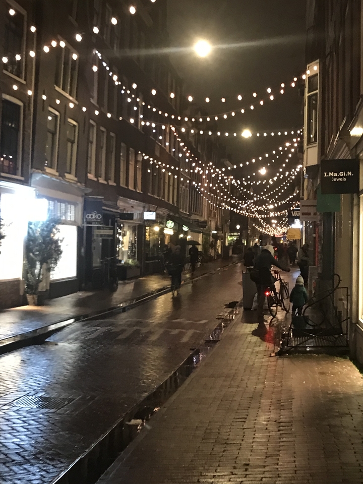 Street in Amsterdam at night with festive lights.