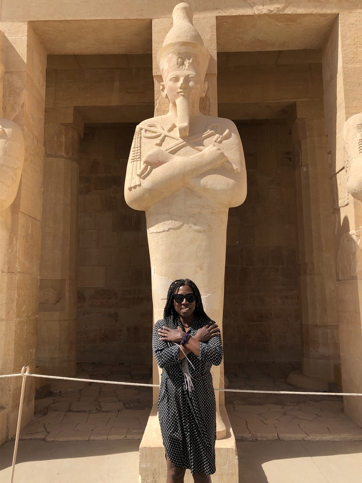 Person posing in front of a large statue.