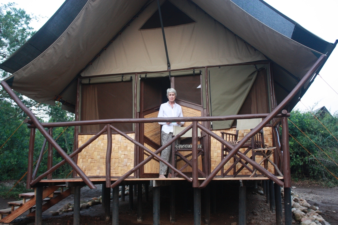 Femme debout sur le balcon d'une tente de safari.